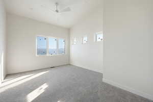 Empty room with carpet flooring, ceiling fan, and vaulted ceiling