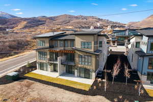 Back of property with board and batten siding, a mountain view, a patio area, and stone siding