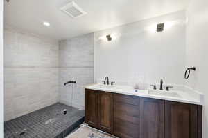 Bathroom with double vanity, recessed lighting, and a tile shower