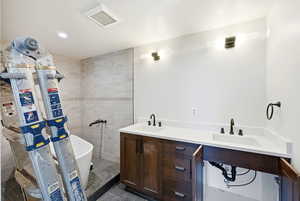 Bathroom featuring double vanity, a soaking tub, dark tile patterned flooring, recessed lighting, and a stall shower