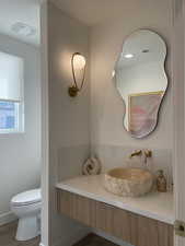 Bathroom with vanity, toilet, wood finished floors, and visible vents