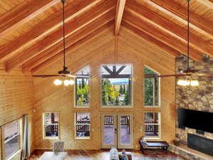 Unfurnished living room with beamed ceiling, high vaulted ceiling, a ceiling fan, and french doors