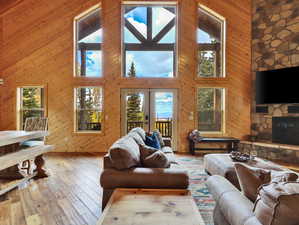 Living area featuring a stone fireplace, a high ceiling, wooden walls, and hardwood / wood-style floors