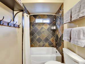 Full bath with toilet and shower / bathtub combination with curtain