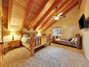 Carpeted bedroom with beam ceiling, high vaulted ceiling, wood ceiling, and a ceiling fan