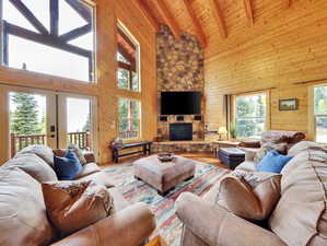 Living area featuring lofted ceiling with beams, wood finished floors, wood walls, a fireplace, and wood ceiling