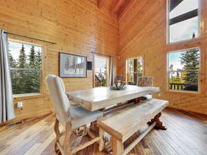 Dining area featuring visible vents, wood walls, a high ceiling, and wood-type flooring