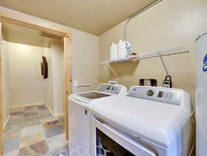 Laundry area featuring baseboards, visible vents, laundry area, stone finish flooring, and washing machine and dryer