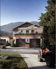 View of front of house featuring an attached garage, a mountain view, concrete driveway, and a balcony