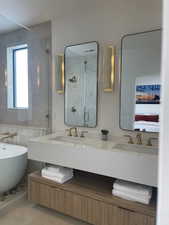 Bathroom with a sink, connected bathroom, a stall shower, and double vanity