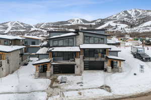 View of front of property featuring a mountain view, stone siding, and an attached garage