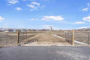 View of yard with a mountain view, fence, a rural view, and a gate