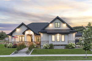 View of front facade featuring stone siding, board and batten siding, a shingled roof, and a front yard