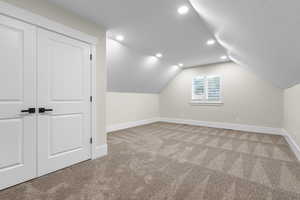 Additional living space with light carpet, recessed lighting, baseboards, and lofted ceiling