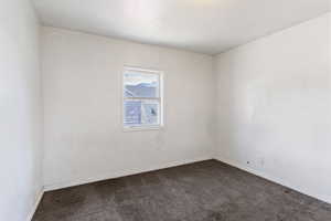 Spare room with dark colored carpet and baseboards