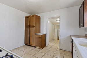 Kitchen with light countertops, light tile patterned floors, brown cabinets, and a textured ceiling