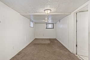 Interior space with a textured ceiling, baseboards, and carpet floors