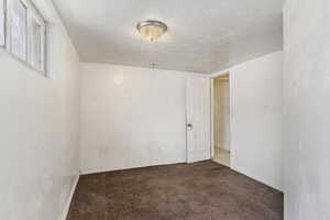 Carpeted spare room featuring baseboards and a textured ceiling