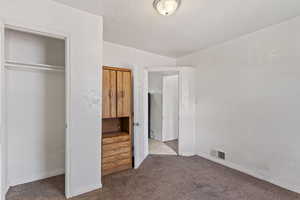 Unfurnished bedroom with baseboards, carpet, visible vents, and a textured ceiling