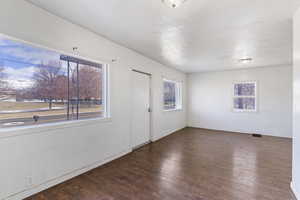 Unfurnished room featuring baseboards, wood finished floors, visible vents, and a textured ceiling