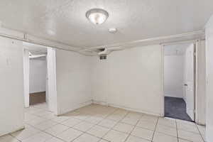 Finished below grade area with light tile patterned floors and a textured ceiling