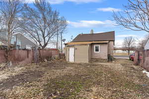 Back of property featuring a shingled roof, a chimney, and fence