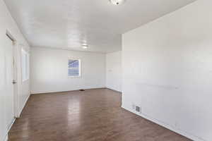 Empty room with visible vents, baseboards, and wood finished floors