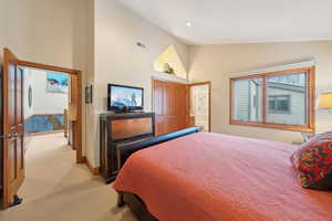 Bedroom with baseboards, high vaulted ceiling, visible vents, and light colored carpet