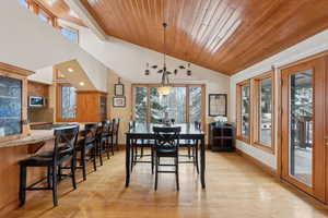 Dining room with light wood-style floors, lofted ceiling, wooden ceiling, and baseboards