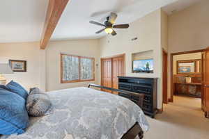 Bedroom with a closet, visible vents, light carpet, ceiling fan, and beamed ceiling