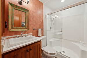 Bathroom with toilet, a stall shower, and vanity