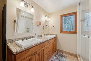 Bathroom featuring double vanity, a sink, baseboards, and tile patterned floors