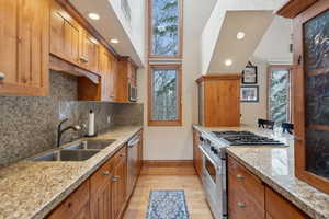 Kitchen with a sink, visible vents, appliances with stainless steel finishes, light wood-type flooring, and brown cabinetry