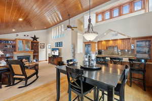 Dining room featuring a warm lit fireplace, wooden ceiling, light wood-style flooring, visible vents, and baseboards