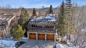 View of front facade with a balcony, driveway, a garage, stone siding, and a mountain view