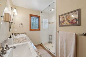 Bathroom with double vanity, a stall shower, a sink, and tile patterned floors