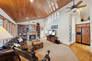 Living room with baseboards, a tiled fireplace, wooden ceiling, light wood-type flooring, and recessed lighting