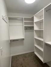 Walk in primary closet featuring built-in organizers