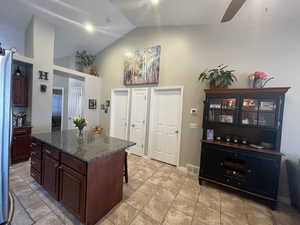 Kitchen with large island, ceiling fan, dark stone counters, and a breakfast bar