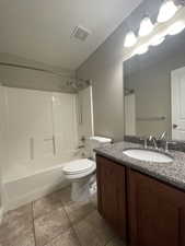 Full bathroom featuring tile flooring, toilet, shower / tub combination, and stone-top vanity