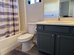 Bathroom with wood finished floors, toilet, shower / bath combo, and vanity