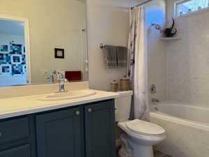 Full bathroom with vanity, toilet, and shower / bath combo with shower curtain