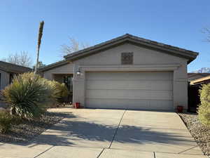 View of front of home with a tile roof, concrete driveway, a garage, and stucco siding