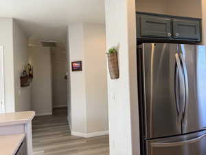 Kitchen with baseboards, light wood finished floors, visible vents, freestanding refrigerator, and light countertops