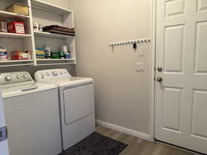 Laundry room featuring washing machine and clothes dryer, laundry area, baseboards, and wood finished floors