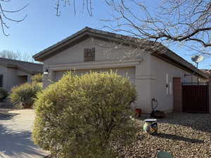 View of property exterior with a tile roof, a garage, driveway, and stucco siding