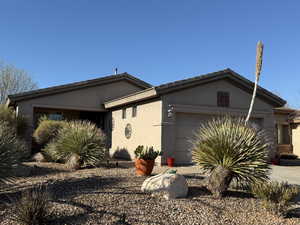 View of front of property featuring a garage, driveway, and stucco siding