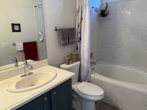 Bathroom with vanity, shower / tub combo, and toilet