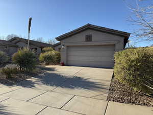 View of front of house with stucco siding, a garage, driveway, and a tiled roof