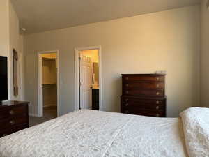 Bedroom featuring a walk in closet, baseboards, and carpet floors